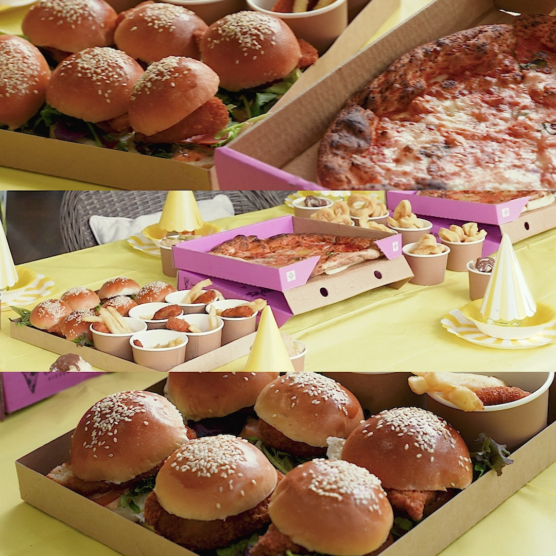 Pizza, sliders, arancini and a cured meat platter laid out on a table.